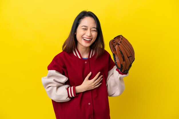 Young vietnamese player woman with baseball glove isolated on yellow background smiling a lot