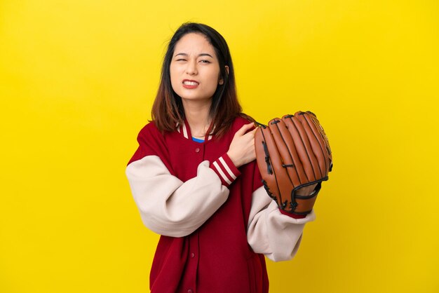 Young Vietnamese player woman with baseball glove isolated on yellow background suffering from pain in shoulder for having made an effort