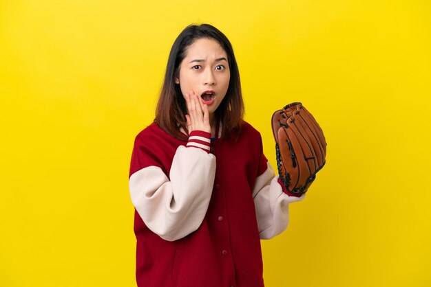 Young Vietnamese player woman with baseball glove isolated on yellow background with surprise and shocked facial expression