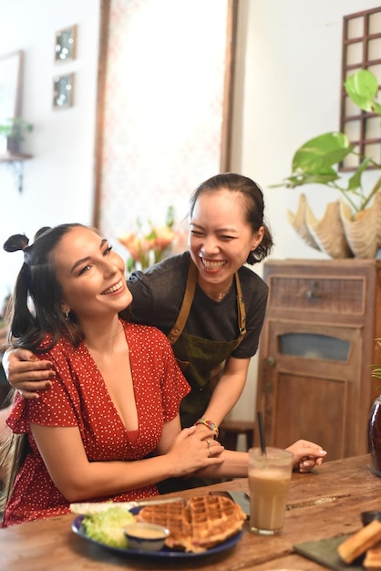 Young Vietnamese waitress smile and hug a friend customer