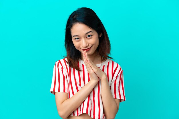 Young Vietnamese woman isolated on blue background keeps palm together. Person asks for something