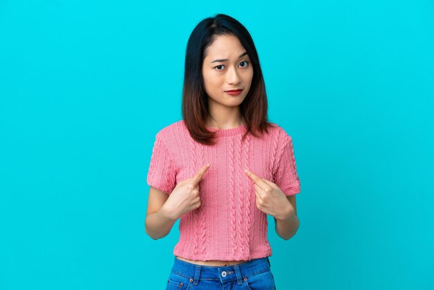 Young Vietnamese woman isolated on blue background pointing to oneself