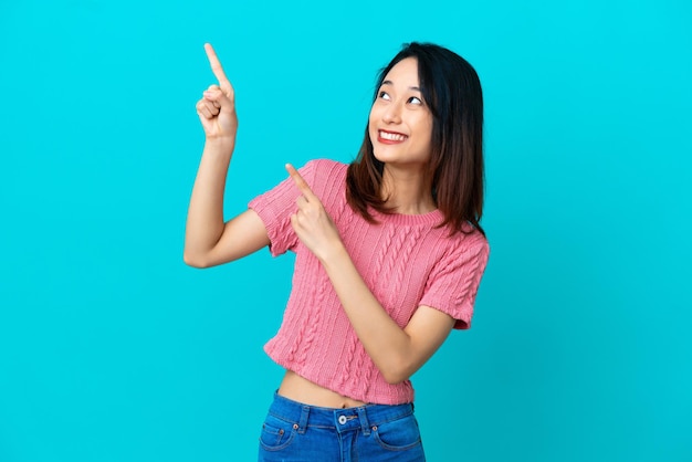 Young Vietnamese woman isolated on blue background pointing with the index finger a great idea