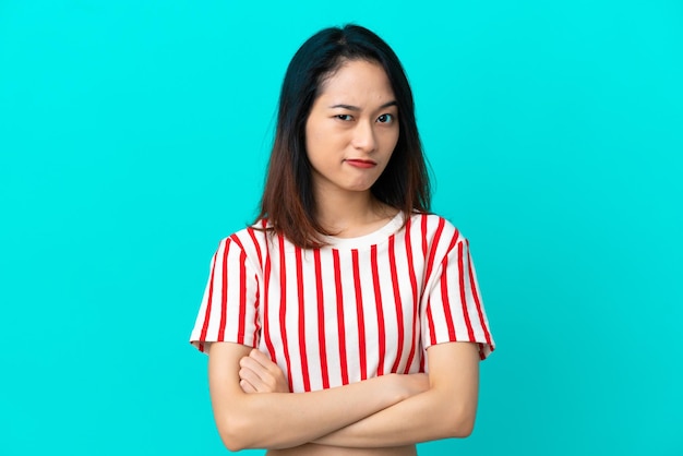 Young Vietnamese woman isolated on blue background with unhappy expression