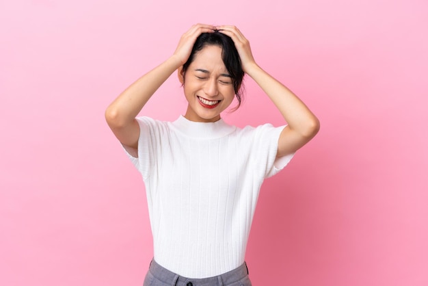 Young Vietnamese woman isolated on pink background laughing