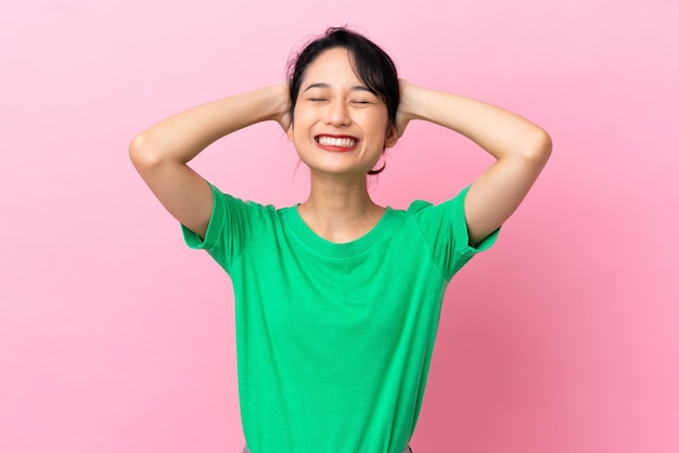 Young Vietnamese woman isolated on pink background laughing