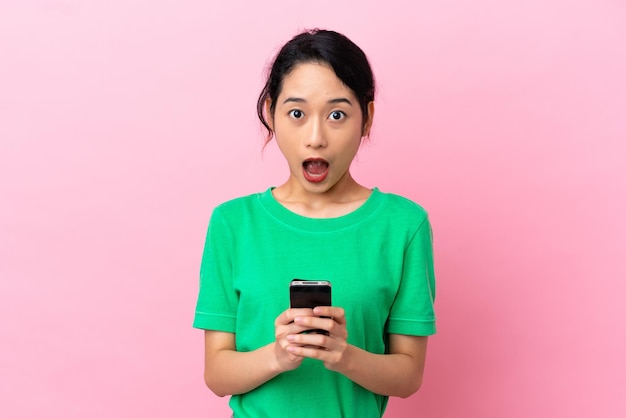 Young Vietnamese woman isolated on pink background surprised and sending a message