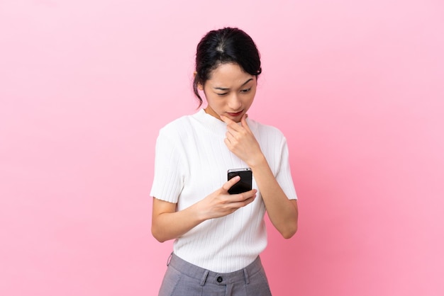 Young Vietnamese woman isolated on pink background thinking and sending a message