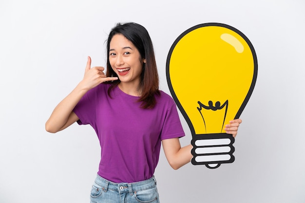 Young Vietnamese woman isolated on white background holding a bulb icon and doing phone gesture