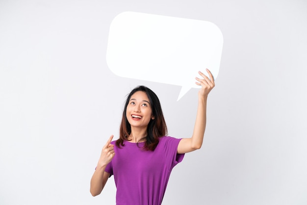 Young Vietnamese woman isolated on white background holding an empty speech bubble and pointing it