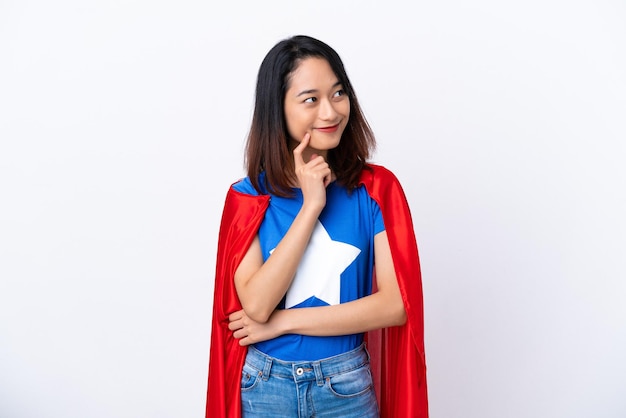 Молодая вьетнамская женщина изолирована на белом фоне в костюме супергероя и думает