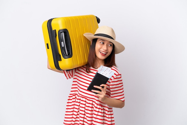 Young Vietnamese woman isolated on white background in vacation with suitcase and passport