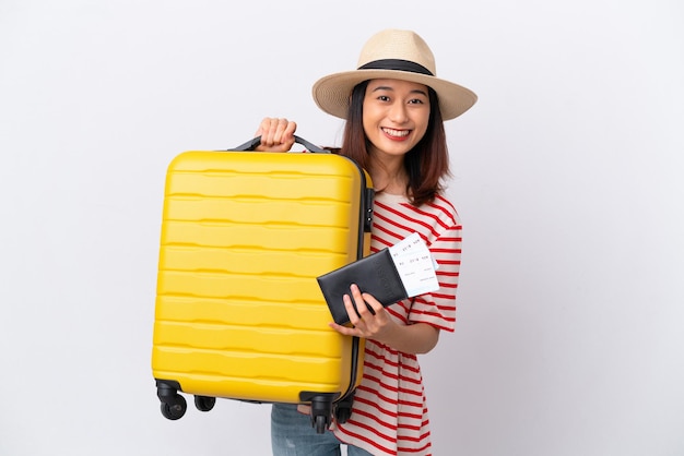 Young Vietnamese woman isolated on white background in vacation with suitcase and passport