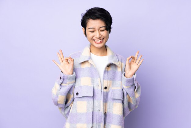 Young Vietnamese woman with short hair over wall in zen pose