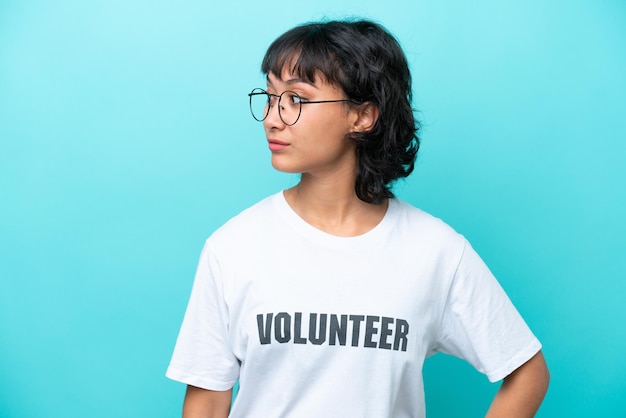 Young volunteer Argentinian woman isolated on blue background looking to the side