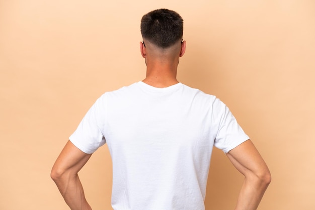 Young volunteer caucasian man isolated on beige background in back position