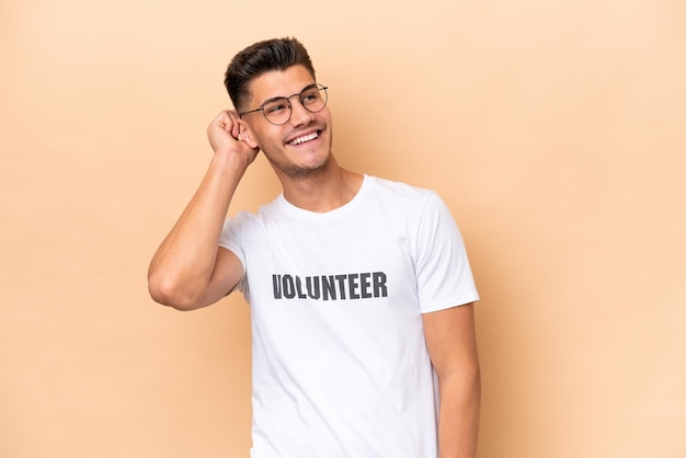 Young volunteer caucasian man isolated on beige background thinking an idea