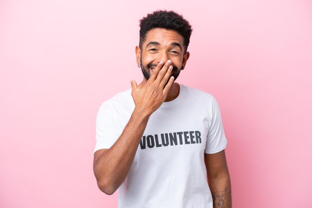 Young volunteer man isolated on pink background happy and smiling covering mouth with hand