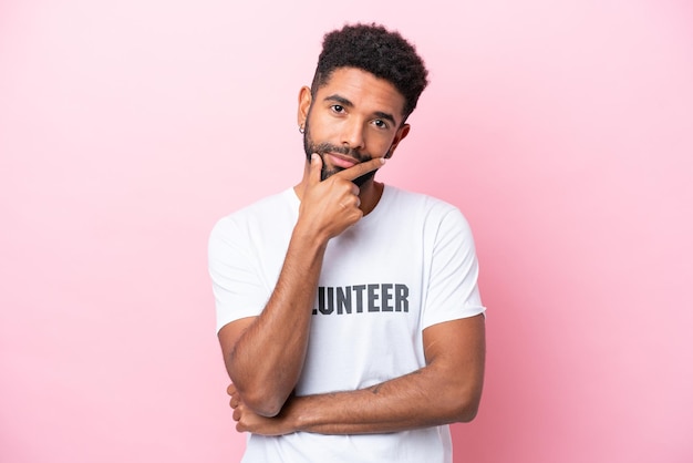 Young volunteer man isolated on pink background thinking