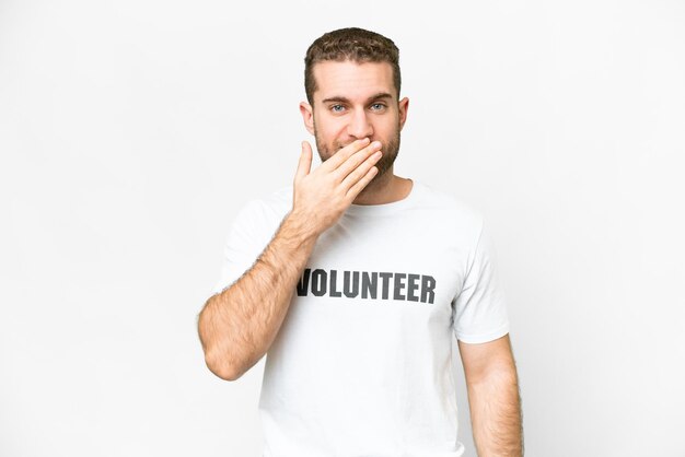 Young volunteer man over isolated white background happy and smiling covering mouth with hand