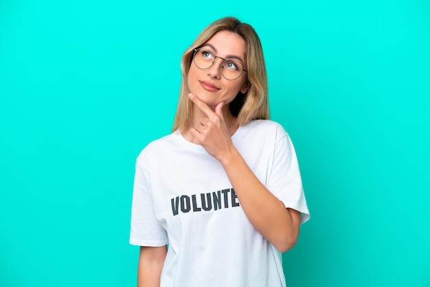 Young volunteer Uruguayan woman isolated on blue background having doubts