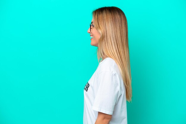 Young volunteer Uruguayan woman isolated on blue background laughing in lateral position