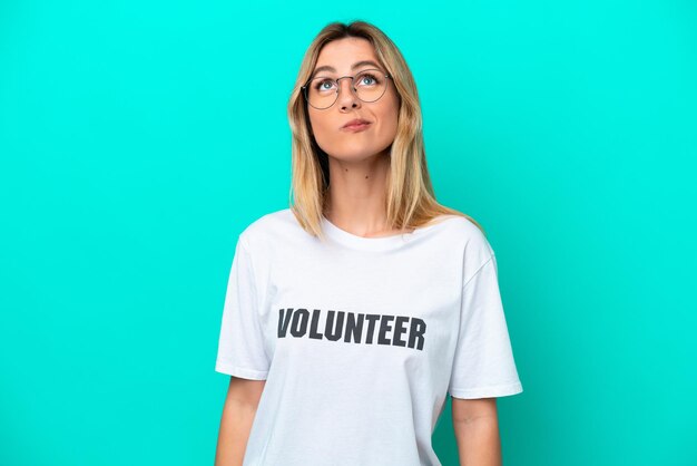 Young volunteer Uruguayan woman isolated on blue background and looking up