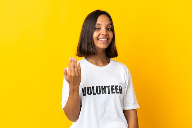 Young volunteer woman isolated inviting to come with hand Happy that you came
