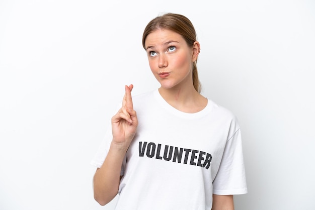 Young volunteer woman isolated on white background with fingers crossing and wishing the best