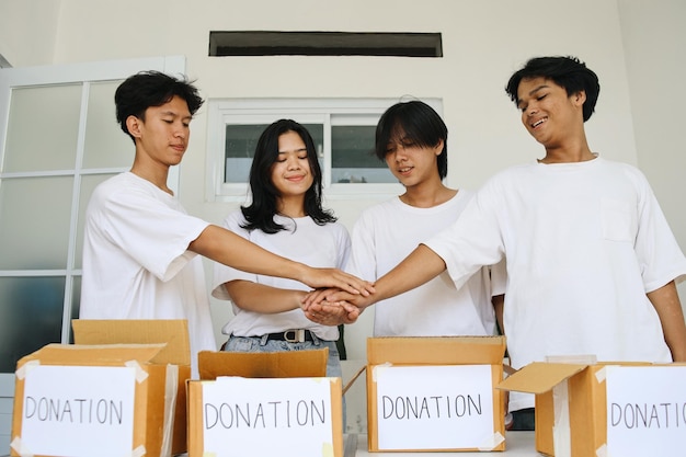 Photo young volunteers stacking hands before distributing boxes of food and drinks for charity event