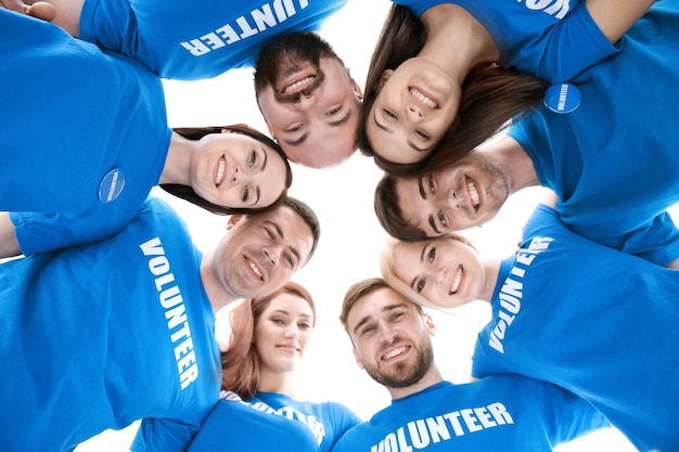 Young volunteers with their heads together in circle on white background