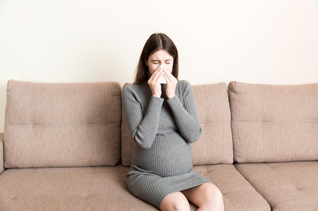 Young vomiting woman sitting on sofa and suffering with nausea Pregnancy expectation concept copy space