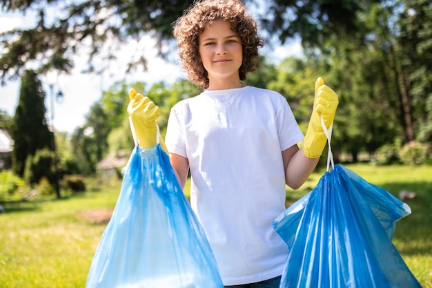 Photo young vounteer holding two bags with garbage