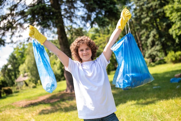 Young vounteer holding two bags with garbage