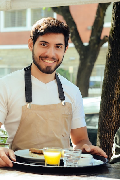 Young waiter holding tray 