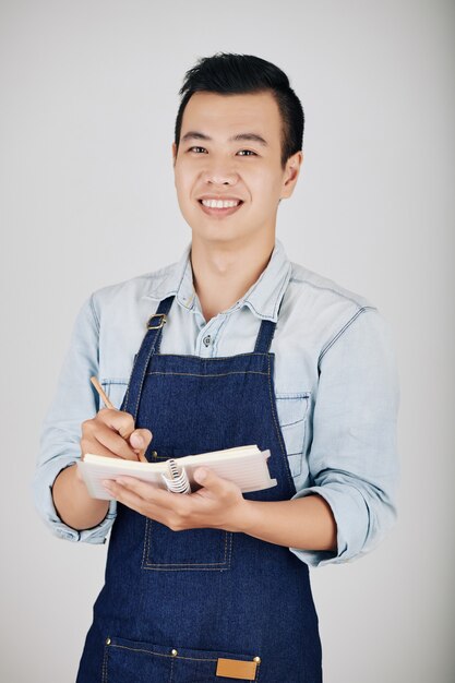 Young waiter taking notes