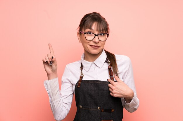 Young waitress over pink with surprise facial expression