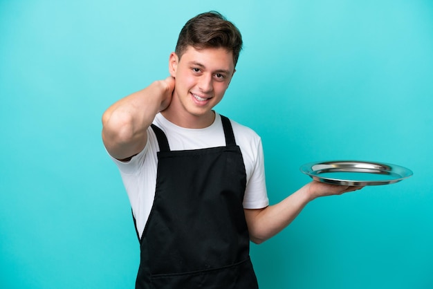 Young waitress with tray isolated on blue background laughing