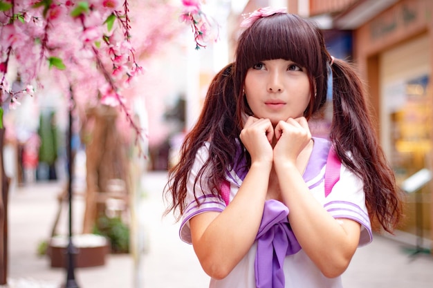 Young wearing school uniform by pink cherry blossoms