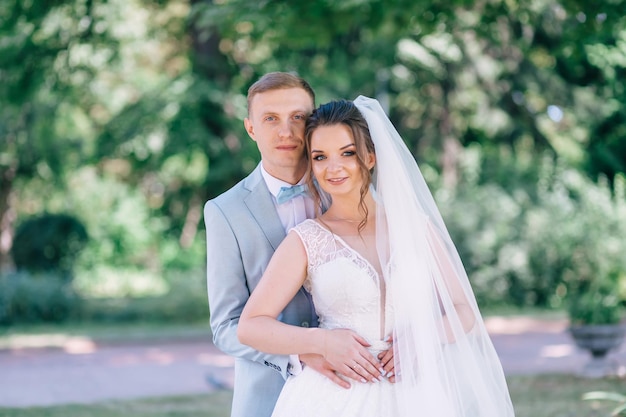 A young wedding couple is enjoying romantic moments on a summer green meadow