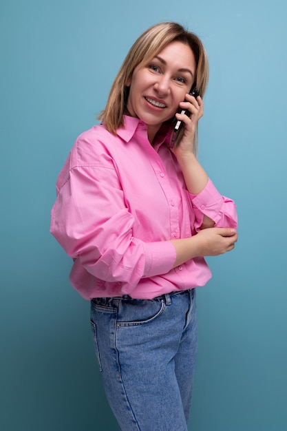 Young wellgroomed blond caucasian woman with flowing hair is dressed in a pink blouse and jeans