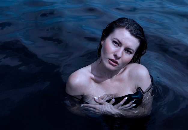 Young wet woman on the background of dark water swimming