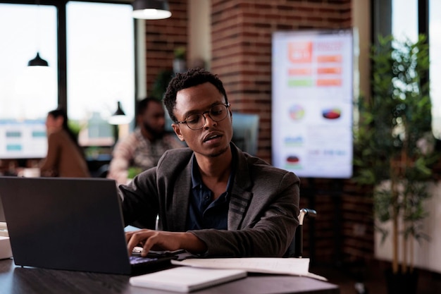 Young wheelchair user with physical health condition working on laptop website, reading email at desk. Paralyzed company employee doing presentation in disability friendly office.