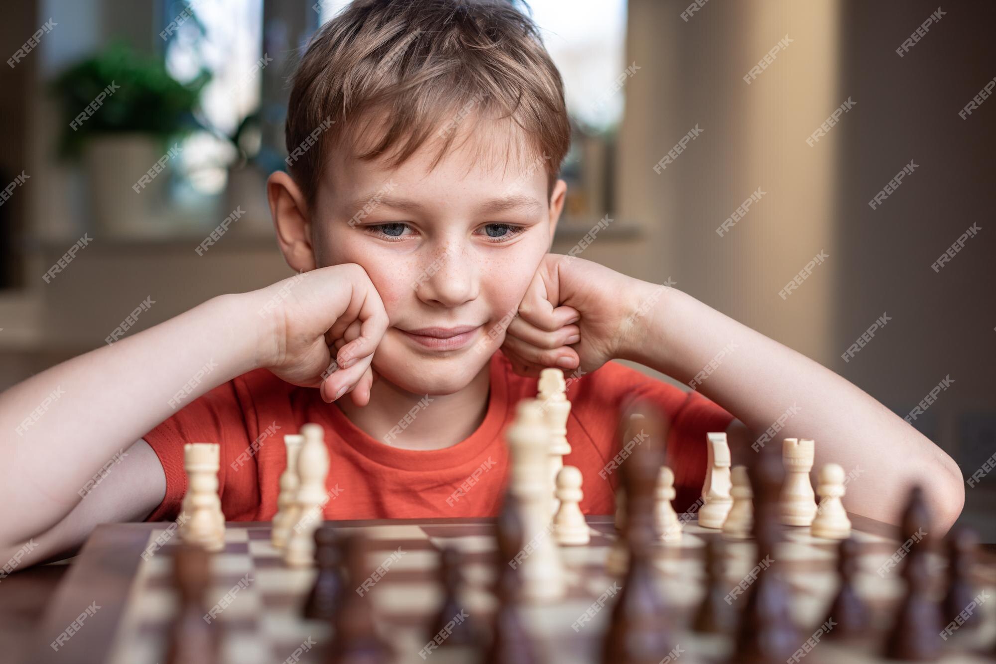 Premium Photo  Young white child playing a game of chess on large chess  board chess board on table in front of school boy thinking of next move