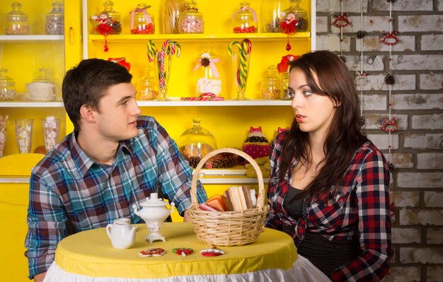 Молодая белая пара в клетчатых рубашках, глядя друг на друга в закусочной во время свидания.