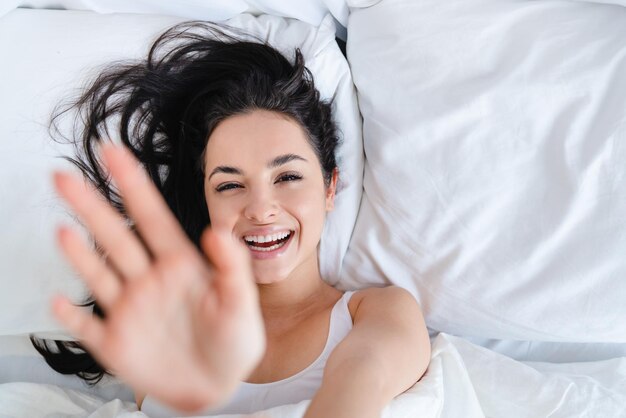 Young white woman doesnt want to get up from her cosy bed early
in the morning