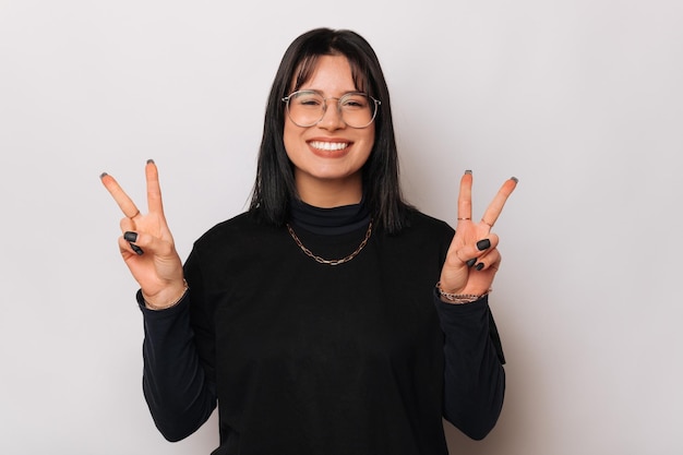 Young wide smiling woman is showing v or peace gesture with both hands