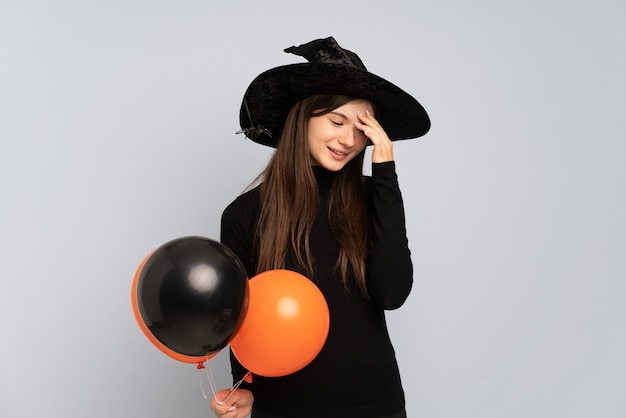 Young witch holding black and orange air balloons