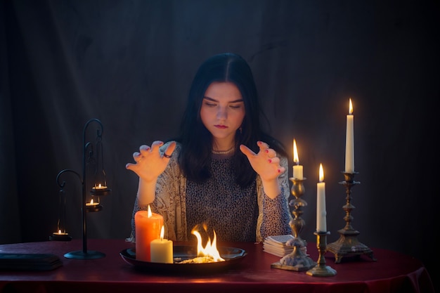 Young witch  with fire and  burning candles on  dark background