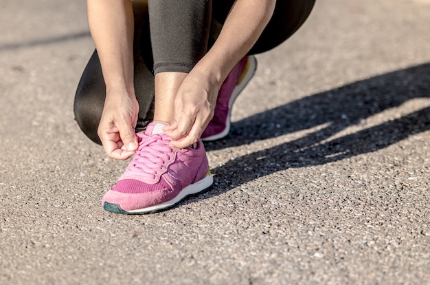 La giovane donna è seduta ad allacciarsi le scarpe da corsa prima di correre nel parco.